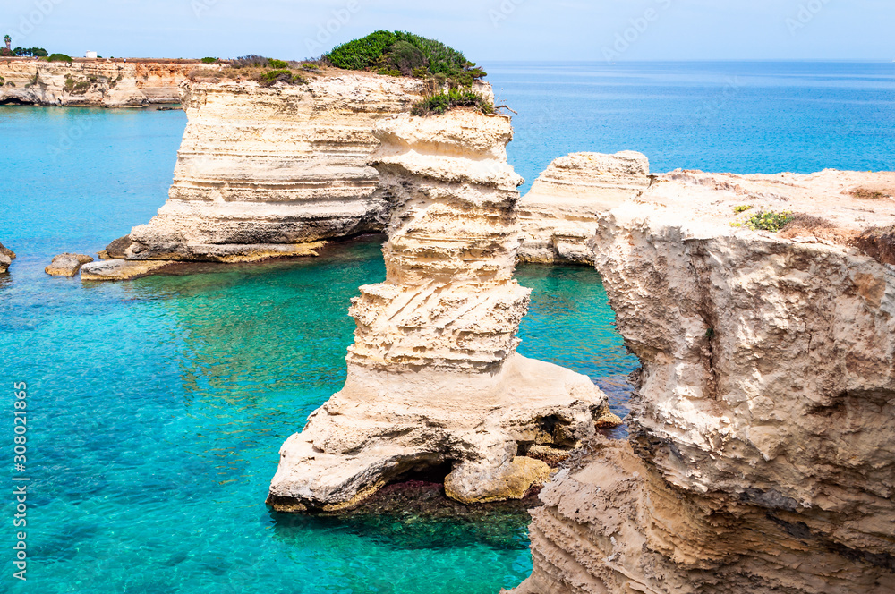 Fototapeta premium Torre Sant Andrea beach with its soft calcareous rocks and cliffs, sea stacks, small coves and the jagged coast landscape. Crystal clear water shape white stone create natural stacks. Melendugno Italy