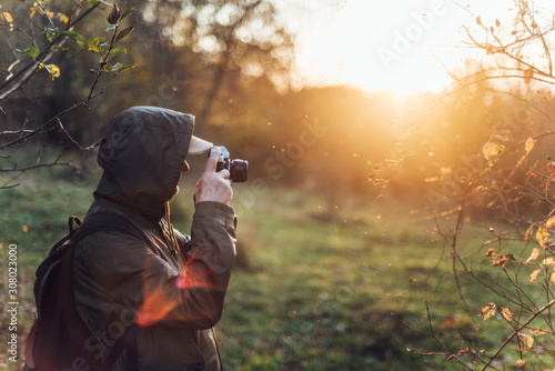 Senior man taking photo in nature. Man photographing autumn forest.