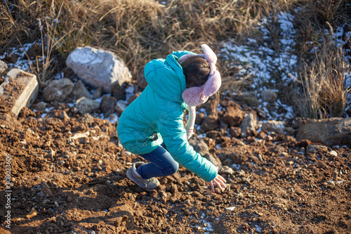 A girl is climbing a mountain. The child is dirty clothes.