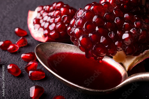 in the foreground a spoon with pomegranate juice and in the background part of the pomegranate with seeds photo