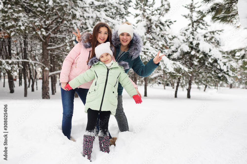 family-mother and two daughters have fun and play against the background of snow-covered trees and forests. Winter fun