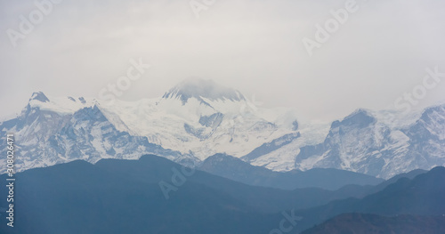 A view of the Annapurna range from the city of Pokhara in the dull, blue light of a misty morning.