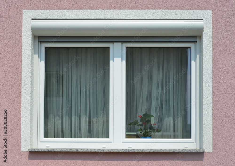 Fototapeta premium Fenster mit Rollladen in einer gemauerten, verputzten und gestrichenen Fassade eines modernen Wohnhauses