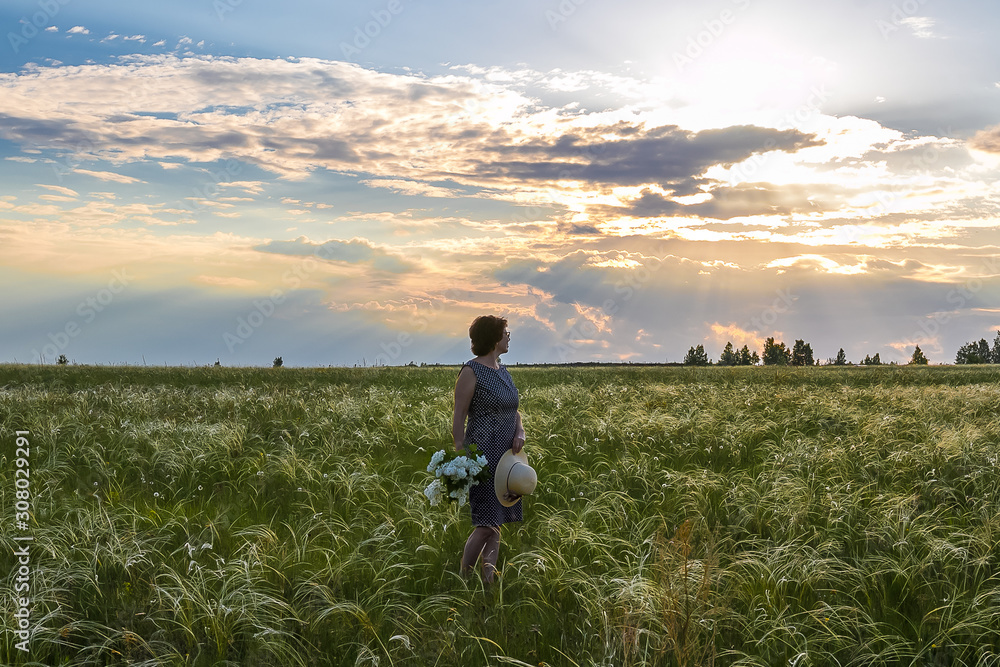 Fototapeta premium Girl in a field at sunset