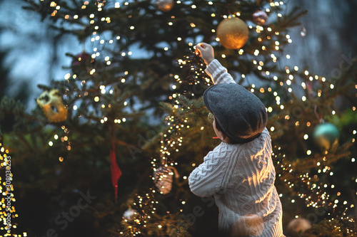 Christmas vintage background with boy, Christmas tree, and light bulbs.