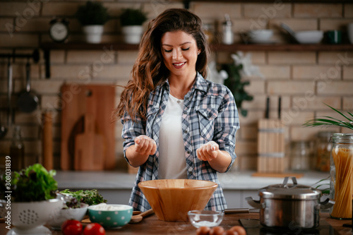 Young woman in kitchen. Beautiful woman playing with flour. © JustLife