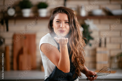 Young woman in kitchen. Beautiful woman playing with flour.