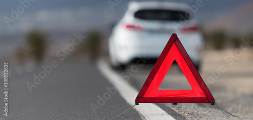 Broken down car with warning triangle behind it waiting for assistance to arrive, red triangle of a car on the road photo