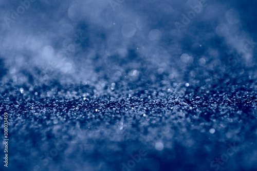 Abstract background with glitter in 2020 classic blue color. Modern sparkly backdrop with beautiful bokeh and copyspace.