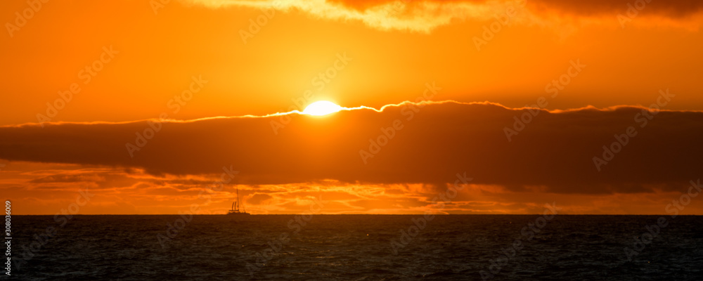 Natural marine landscape with amazing sunset over the ocean in Tenerife Canary Island Spain. Summer exotic vacation postcard from tropical island. Wonderful orange sunrise over the water behind clouds