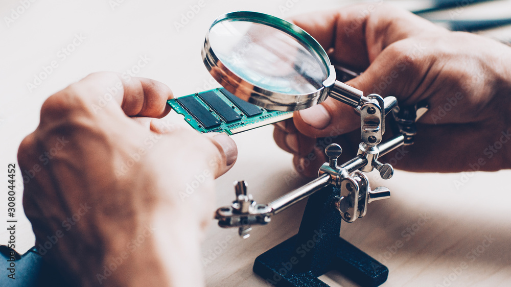 Electronics expertise. Microcircuits, magnifier Technician examining components