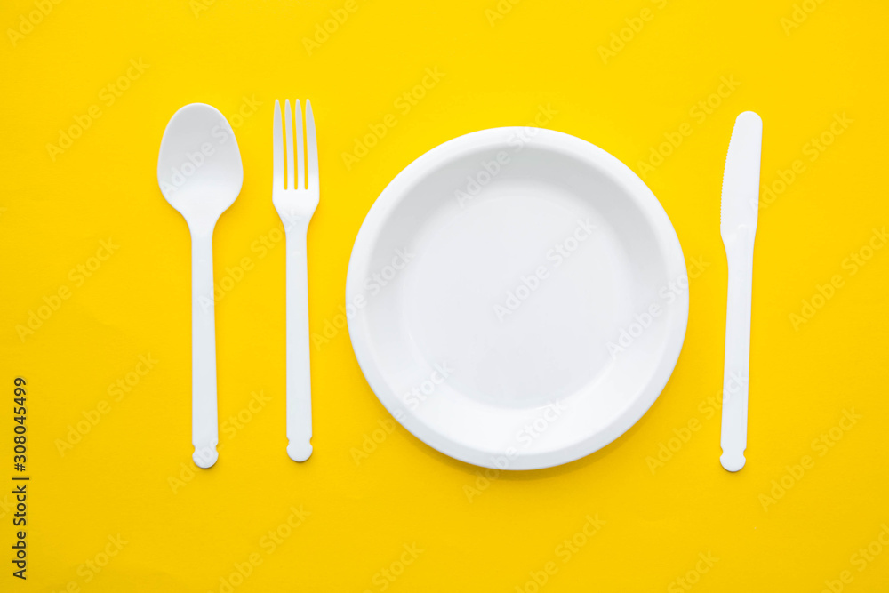 Plastic white fork, knife, spoon and plate on yellow background. Cooking utensil. Top view. Minimalist Style. Copy, empty space for text Plastic white fork, knife, spoon and plate on yellow background. Cooking utensil. Top view. Minimalist Style. Copy, empty space for text
