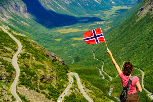 Tourist with norwegian flag on Trollstigen viewpoint