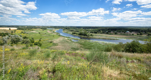 View on a river in a bright summer day. Picturesque countryside landscape. Green grass  cloudy sky.