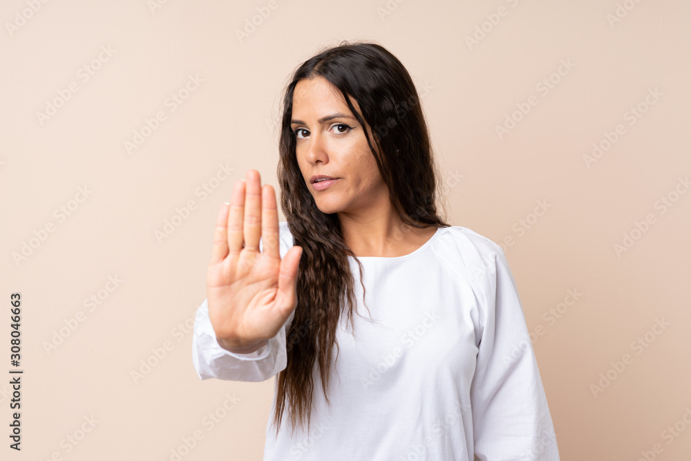 Young woman over isolated background making stop gesture with her hand Young woman over isolated background making stop gesture with her hand