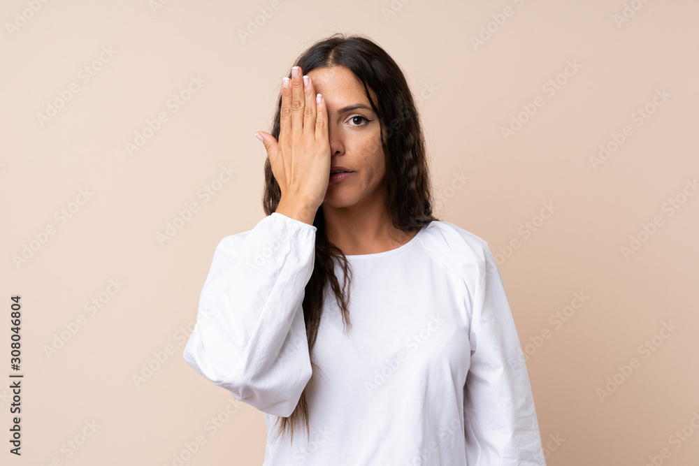 Young woman over isolated background covering a eye by hand Young woman over isolated background covering a eye by hand