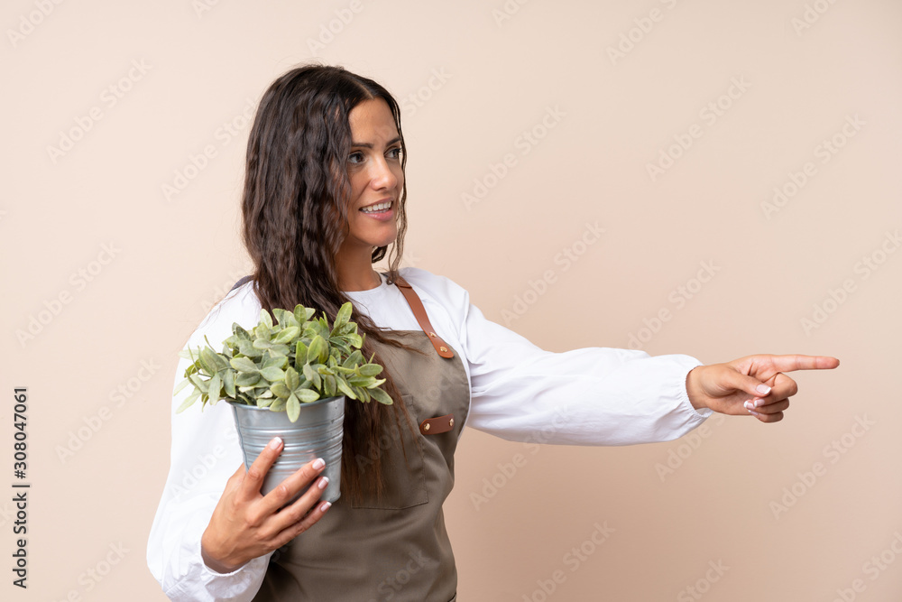 Young woman holding a plant pointing to the side to present a product Young woman holding a plant pointing to the side to present a product