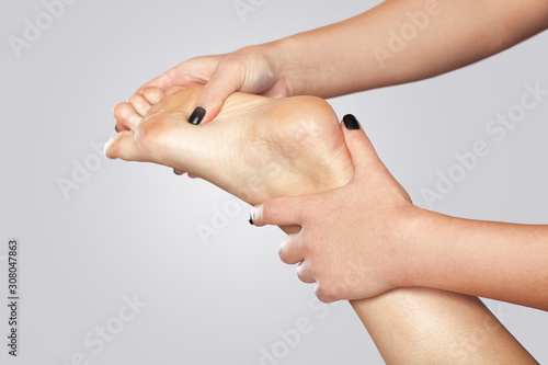 An orthopedic doctor does massage of the foot and lower leg of the patient after an injury Sprained ankle in the clinic.Cosmetology and massage concept.