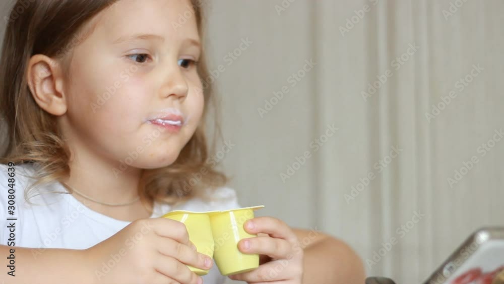 Baby girl eats dairy product yogurt. Child eating cottage cheese with a spoon. Portrait closeup Baby girl eats dairy product yogurt. Child eating cottage cheese with a spoon. Portrait closeup