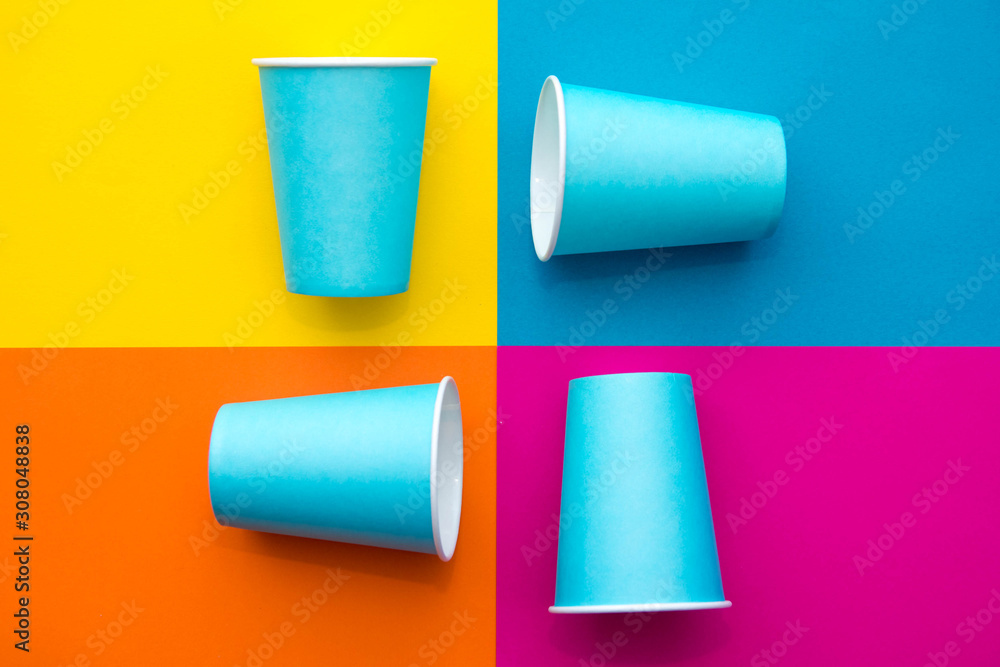 Blue paper disposable cups on beautiful multicolored background. Top view. Minimalist Style. Copy, empty space for text Blue paper disposable cups on beautiful multicolored background. Top view. Minimalist Style. Copy, empty space for text