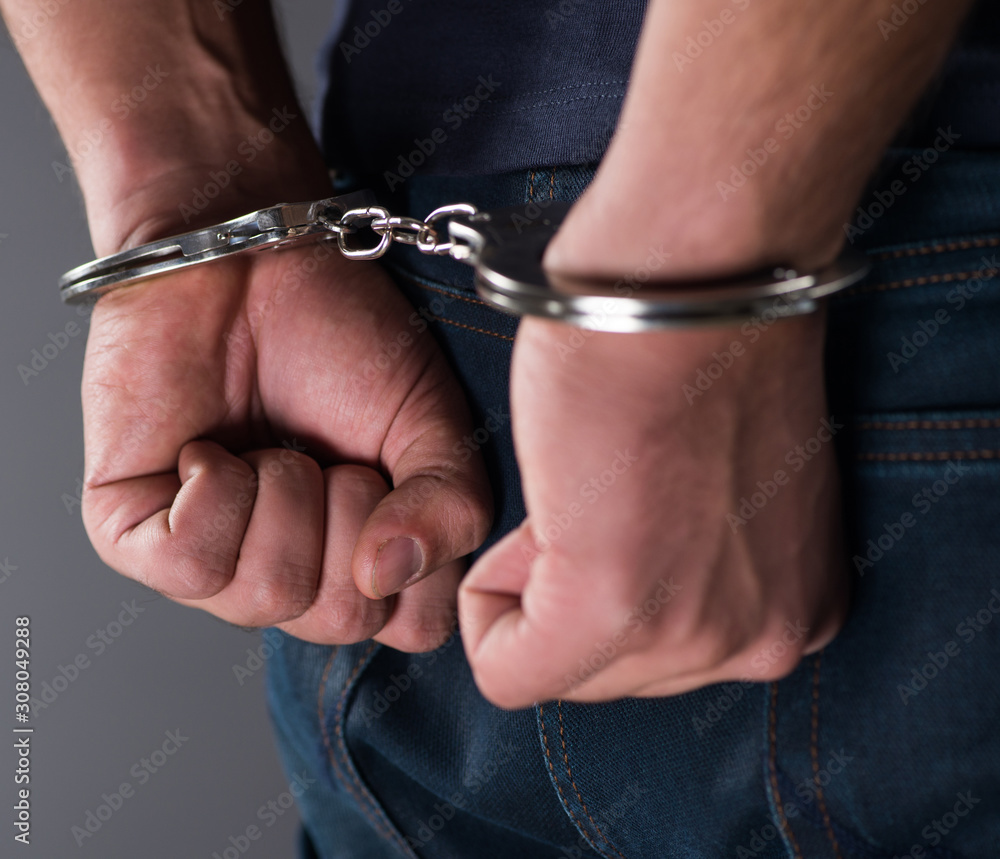 Man with his hands handcuffed in criminal concept