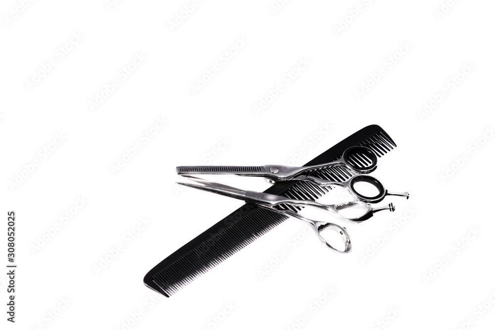 Obraz premium Two hairdressing scissors and a comb on a white background