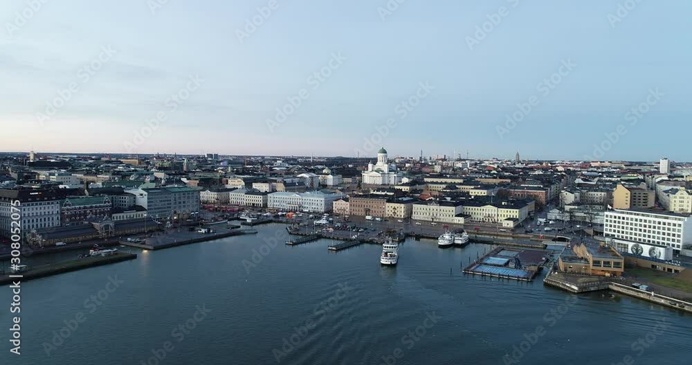 Cinematic aerial winter view during sunset. Buildings, snow, sea, cityscape and drone flying forward. Helsinki market square at evening. Winter season. Cinematic aerial winter view during sunset. Buildings, snow, sea, cityscape and drone flying forward. Helsinki market square at evening. Winter season.