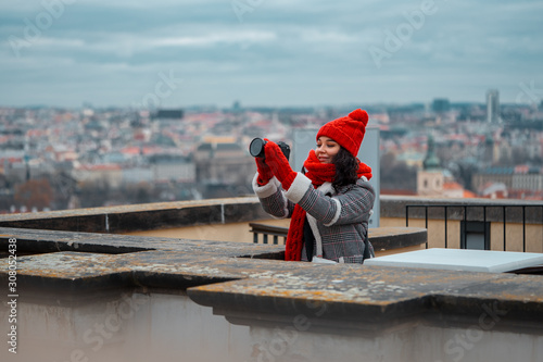 Wide Shot Of Young Attractive Woman With Big Red Scarf Making Photos Of Romantic View To The Gothic Cityscape of Prague.