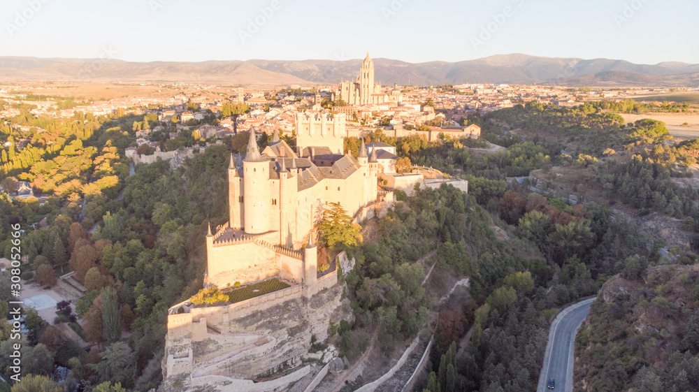 Historic medieval Castle in Segovia, Spain. Drone aerial view with sunset light of spanish stronghold in old town with monument cathedral. History prison, alcazar of Segovia, world heritage.