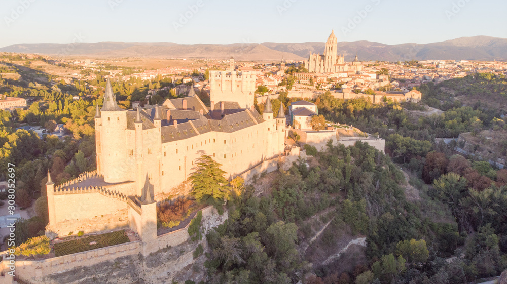 Historic medieval Castle in Segovia, Spain. Drone aerial view with sunset light of spanish stronghold in old town with monument cathedral. History prison, alcazar of Segovia, world heritage.