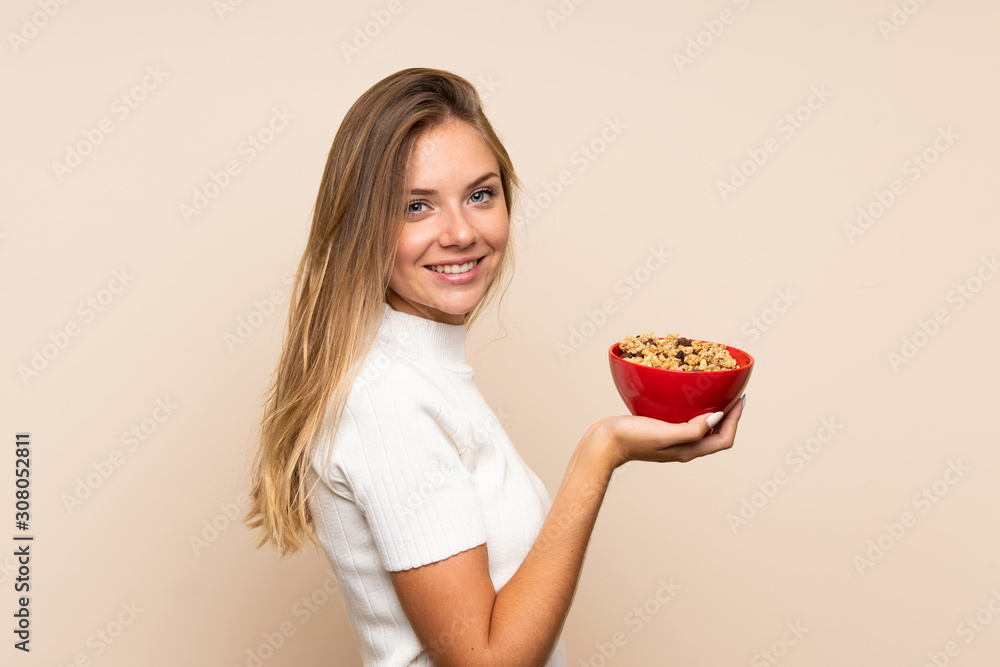 Young blonde woman over isolated background holding a bowl of cereals Young blonde woman over isolated background holding a bowl of cereals