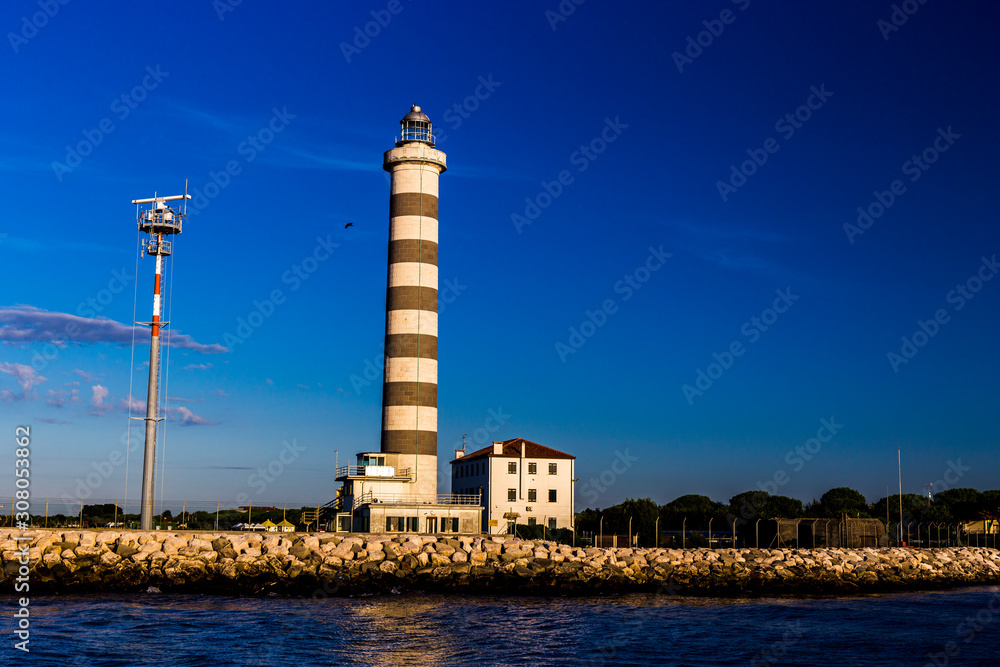 View at the lighthouse in the bay with beautiful blue sky. Sunrise time. Jesolo, Italy.