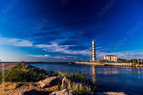 View at the lighthouse in the bay with beach on the other side and beautiful blue sky. Sunrise time. Jesolo, Italy. photo