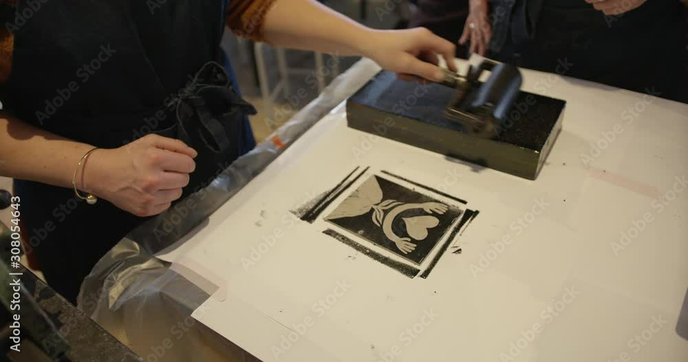 hand rolling ink on to the ink roller. rolling ink on the lino cutout art design. rolling ink out on a block. making artwork. hand rolling ink on to the ink roller. rolling ink on the lino cutout art design. rolling ink out on a block. making artwork.