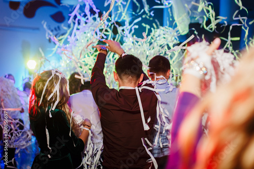Portrait of newlywed couple and their friends at the wedding party showered with confetti in banquet hall. photo