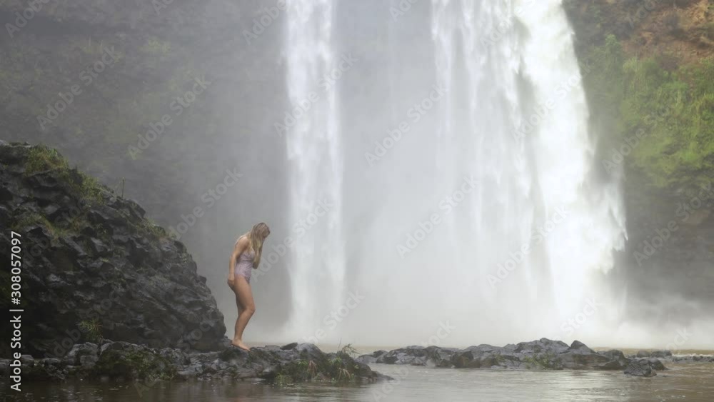 Young Woman Walking in front of a Large Waterfall (Wailua Falls) on Kauai, Hawaii, Static shot Young Woman Walking in front of a Large Waterfall (Wailua Falls) on Kauai, Hawaii, Static shot