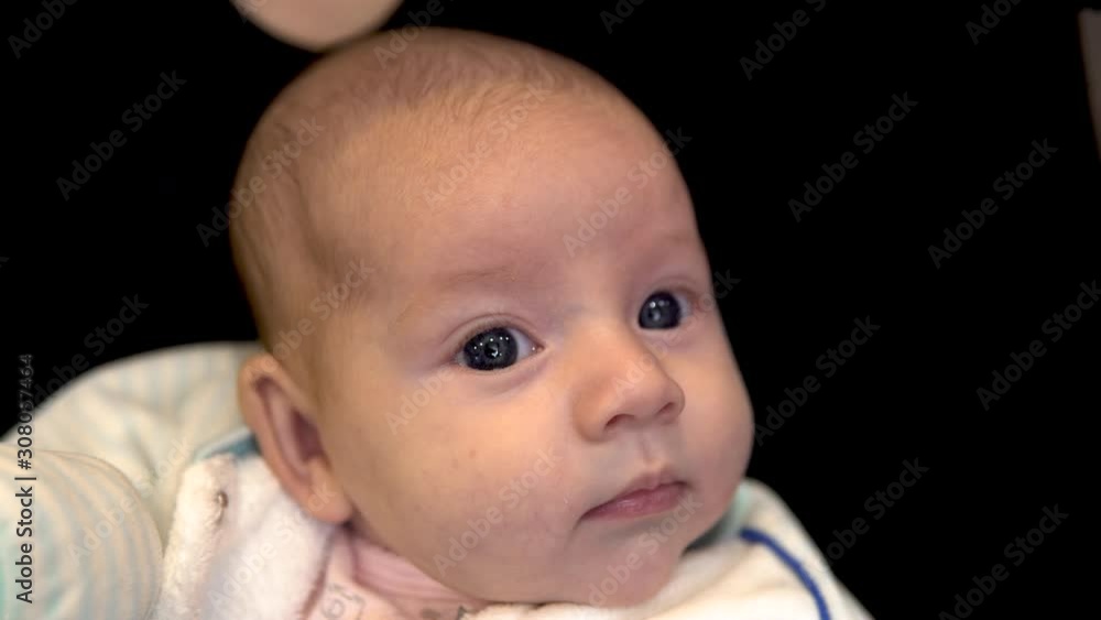 Baby in the arms of her mother. The child spins and looks in different directions. Face close up Baby in the arms of her mother. The child spins and looks in different directions. Face close up