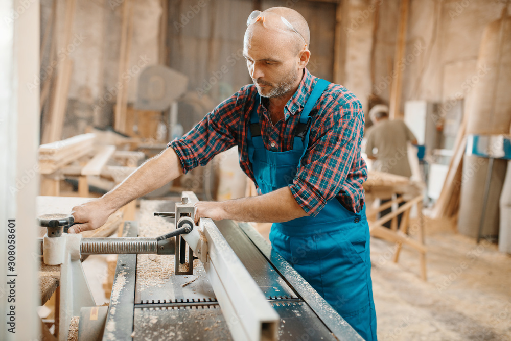 Carpenter processes board on plane machine Carpenter processes board on plane machine
