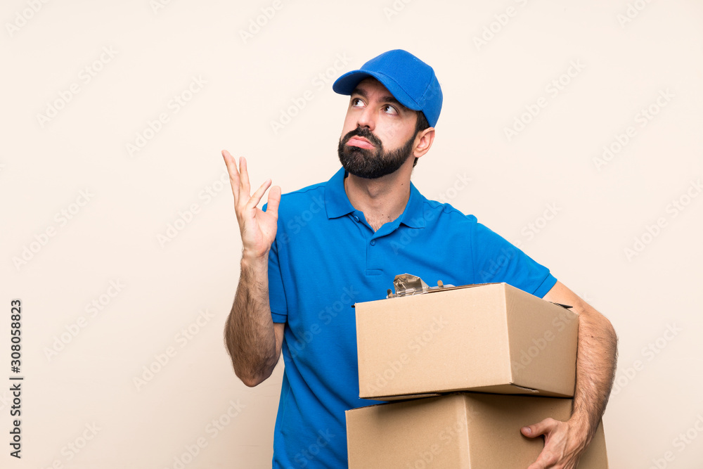 Delivery man with beard over isolated background frustrated by a bad situation Delivery man with beard over isolated background frustrated by a bad situation
