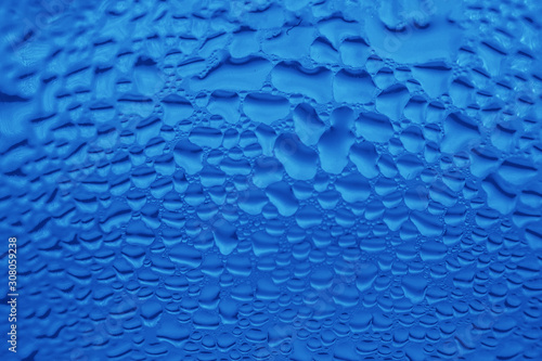 Water rain drops on glass surface in trendy color of the years classic blue. Abstract background backdrop for poster banner