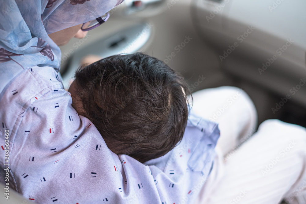 Close of baby boy's head breastfeeding his mother breast in a car
