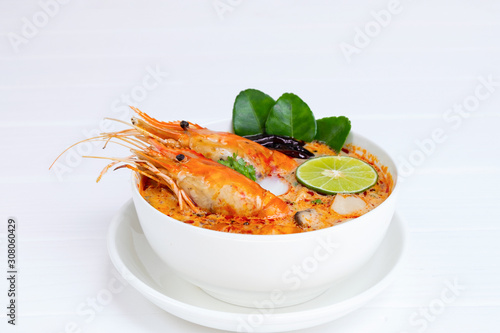 Tom Yum Goong or Shrimp soup spicy sour Soup Traditional food in Thailand contains chili, lime, ginger, galangal, lemongrass, lime leaf,  white wood background. photo