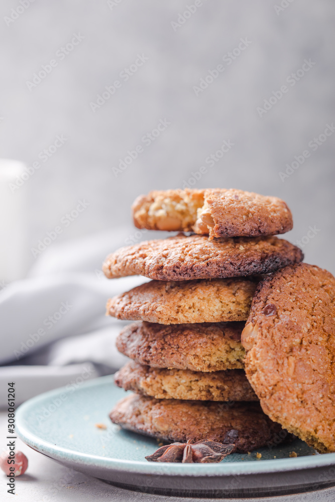 Homemade organic oatmeal cookies with peanuts  and bottle of milk on light concrete background.