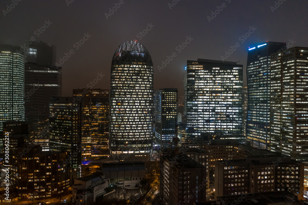 Aerial drone night shot of Skyscrapers with lights on in La Defense, financial district of Paris