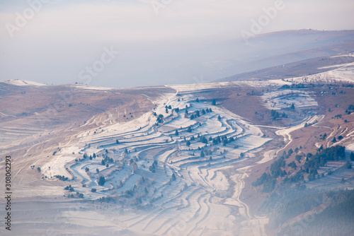 Terraced field in the valley at wintertime, dense fog, view from the top of a mountain in the Carpathian mountains.