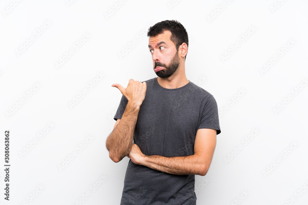 Young handsome man over isolated white background unhappy and pointing to the side Young handsome man over isolated white background unhappy and pointing to the side