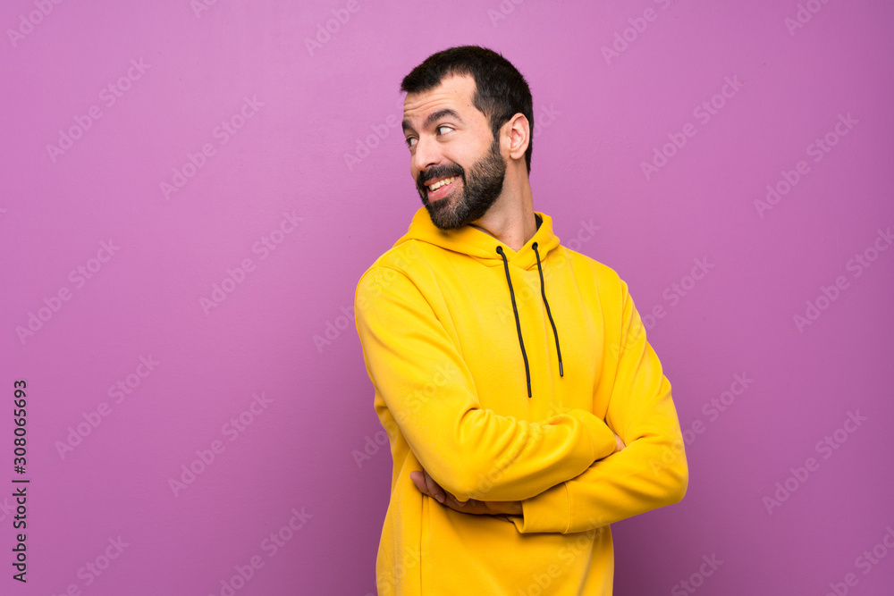 Handsome man with yellow sweatshirt with arms crossed and happy Handsome man with yellow sweatshirt with arms crossed and happy