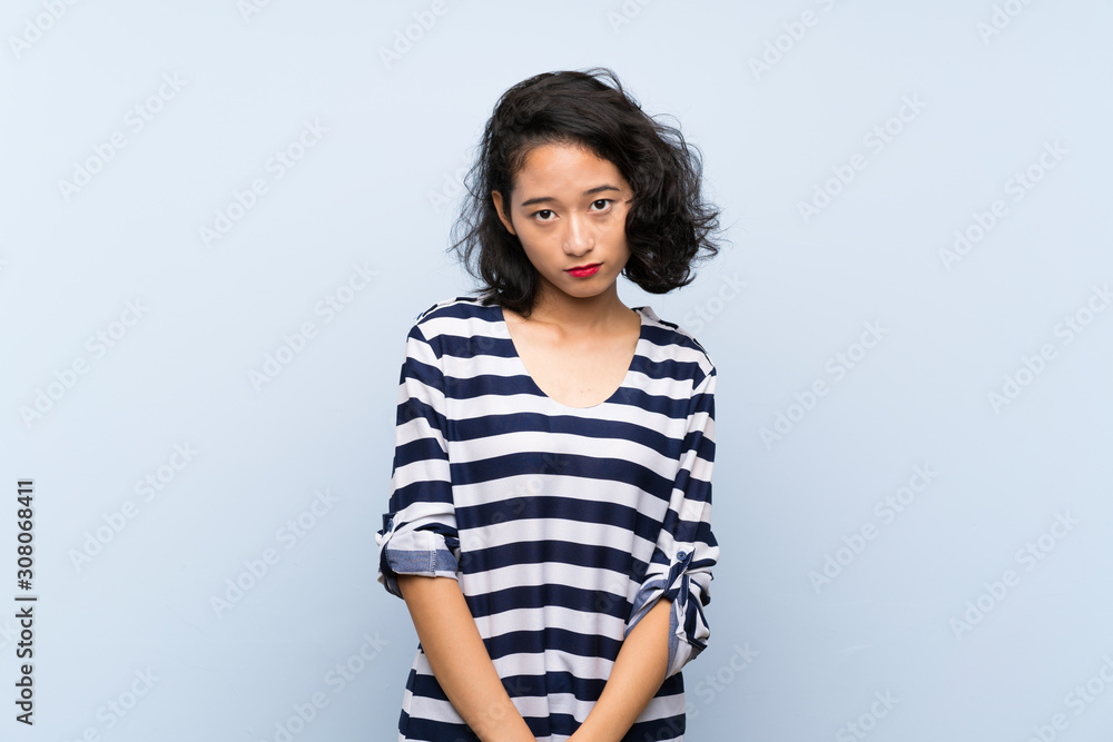 Asian young woman over isolated blue background with sad and depressed expression Asian young woman over isolated blue background with sad and depressed expression