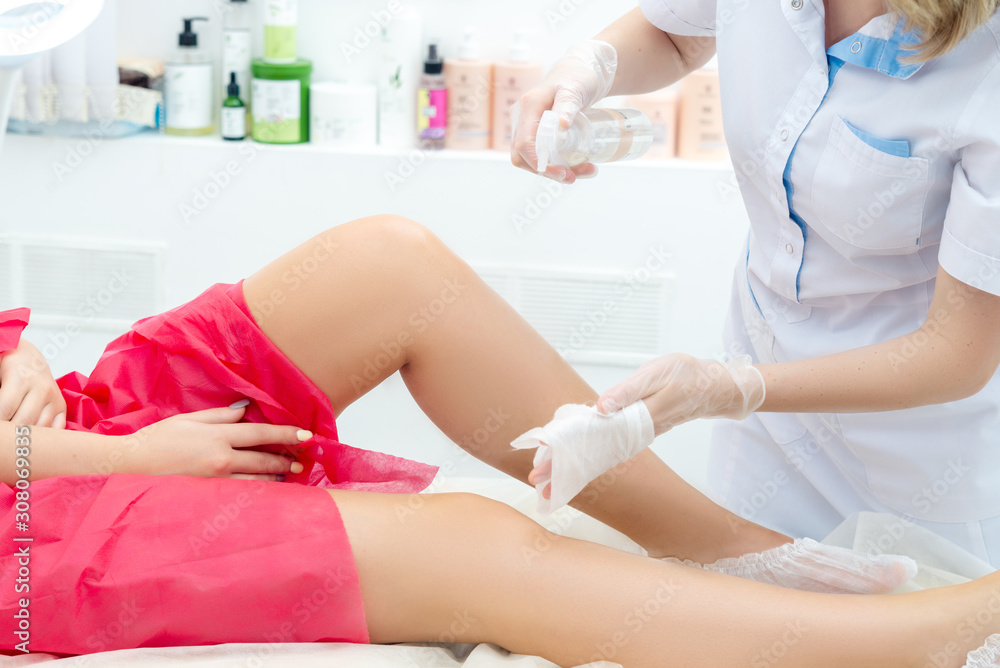beautician hair removal procedure on the client's feet in beauty parlor