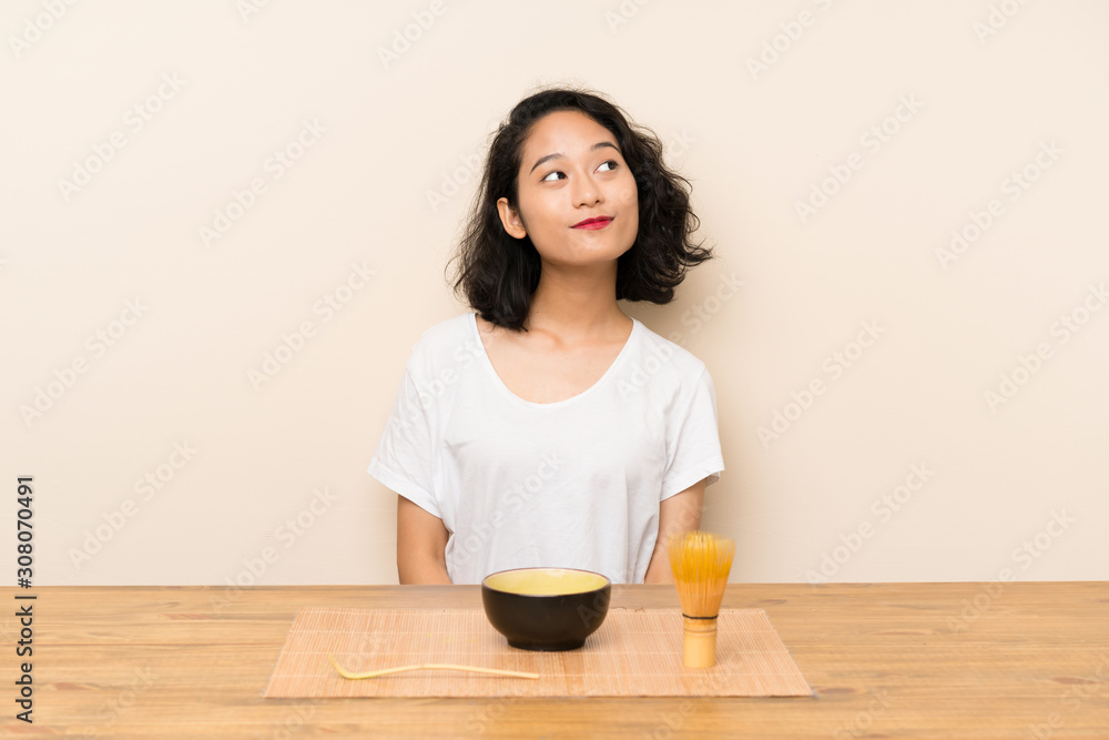 Young asian girl with tea matcha looking up while smiling Young asian girl with tea matcha looking up while smiling